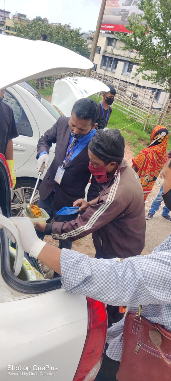 Team member serving hot food from a car.