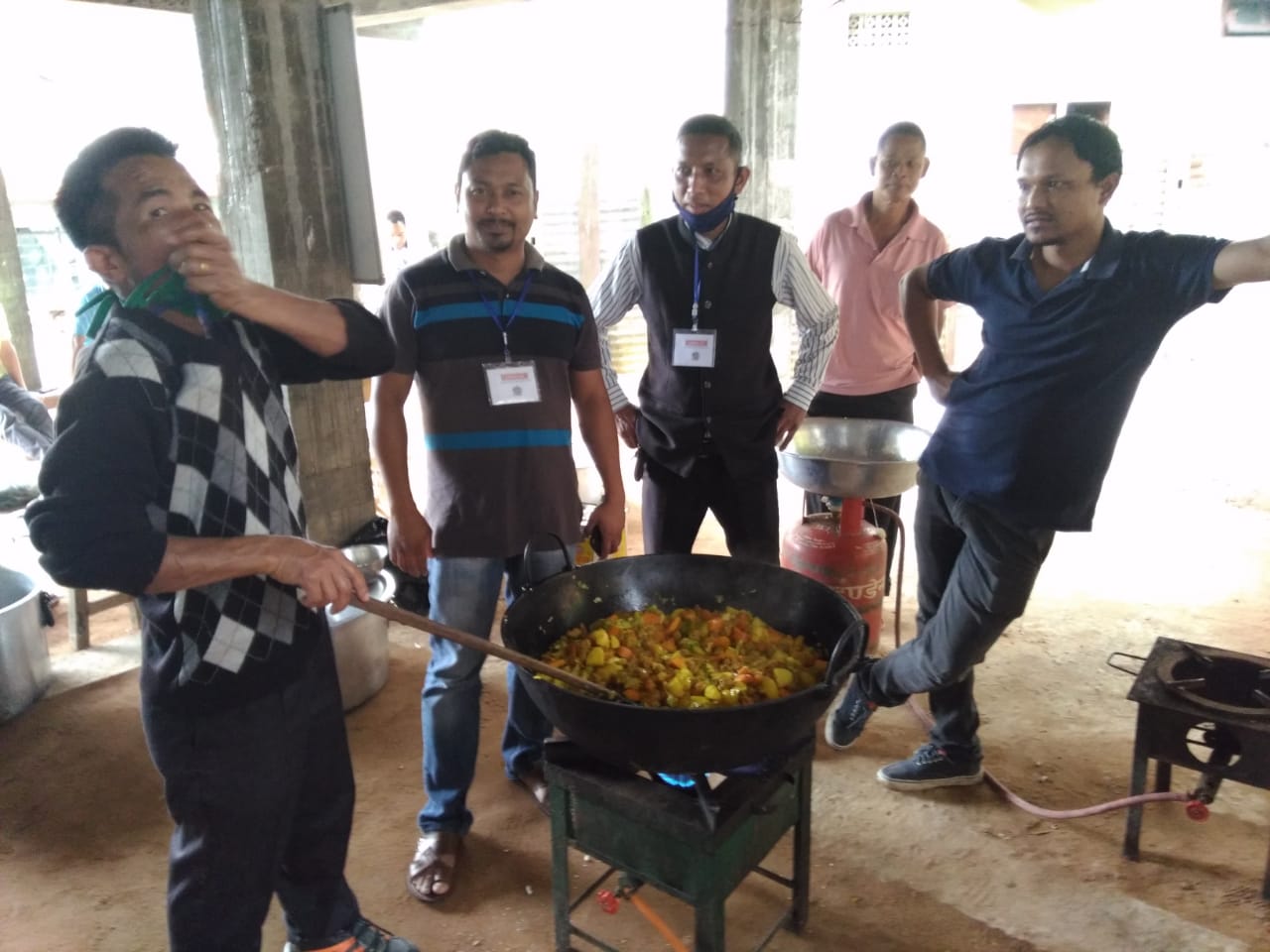 Team members cooking food together for distribution.