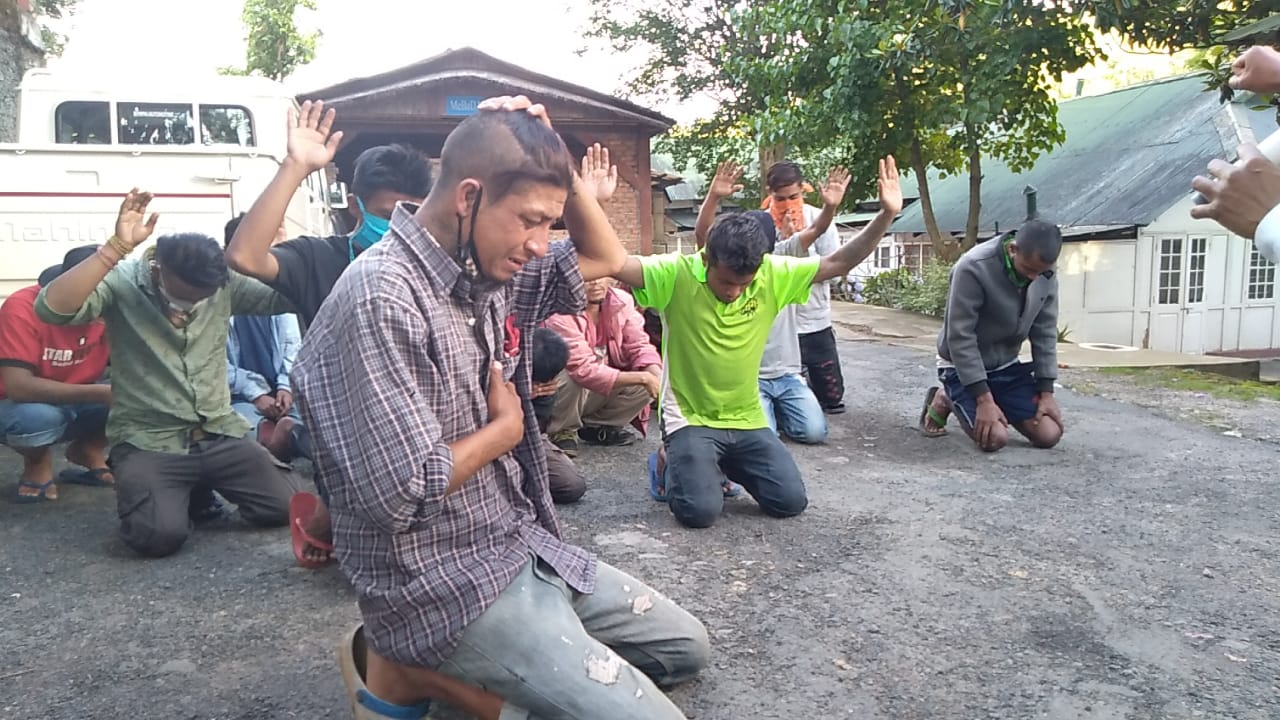 Men kneeling in prayer during an outdoor service.